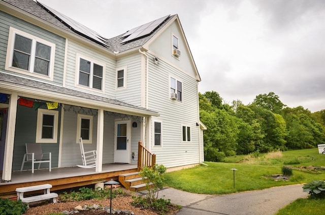 35 Village Ln Unit 35, Berlin, MA 01503 - view of front of house featuring covered porch, a front yard, roof mounted solar panels, roof with shingles, and cooling unit