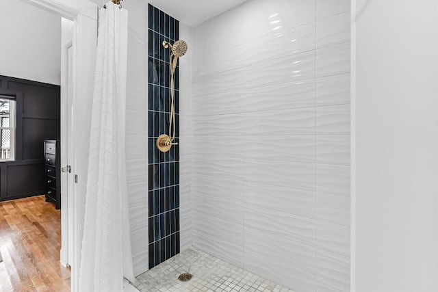 bathroom with a tile shower and wood finished floors