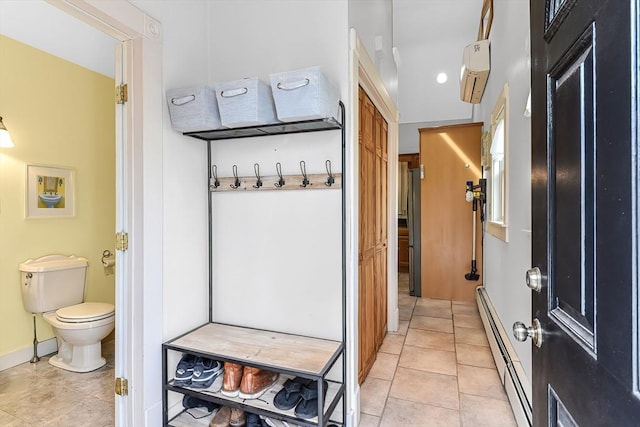 interior space with tile patterned floors, toilet, baseboards, and a baseboard radiator