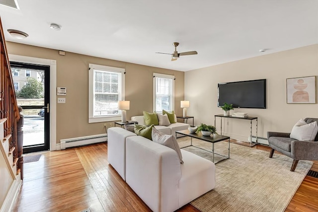 living room featuring baseboard heating, visible vents, and light wood-style floors