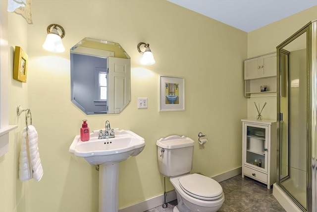 bathroom with tile patterned floors, toilet, a stall shower, a sink, and baseboards