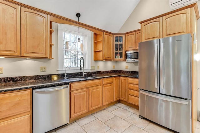 kitchen featuring dark stone counters, a wall unit AC, vaulted ceiling, appliances with stainless steel finishes, and a sink