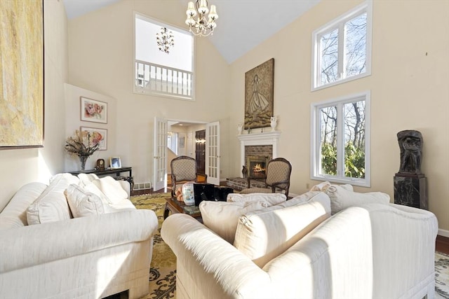 living room with a notable chandelier, a fireplace, french doors, and high vaulted ceiling