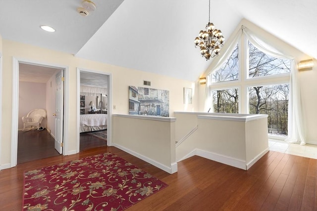 hall with high vaulted ceiling, dark wood-type flooring, and a chandelier