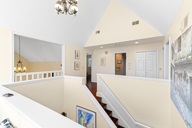 staircase with vaulted ceiling, a chandelier, and wood-type flooring