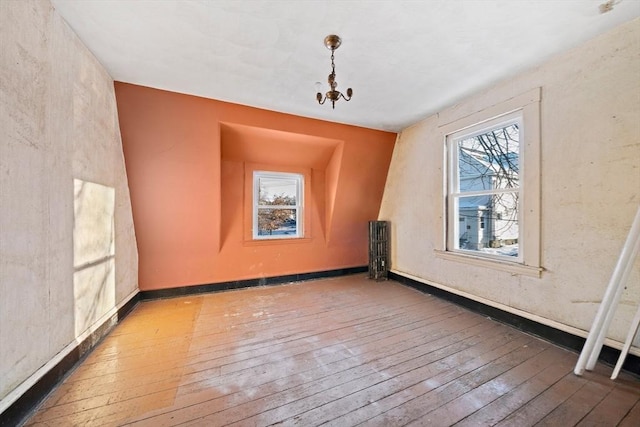 bonus room featuring radiator heating unit, wood-type flooring, and a chandelier