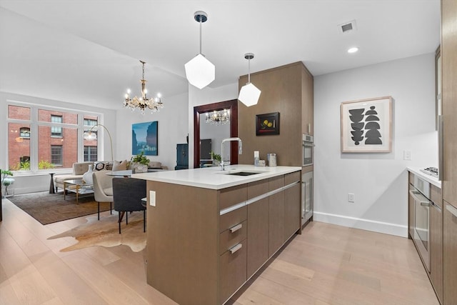 100 Lovejoy Wharf Unit 5N, Boston, MA 02114 - kitchen with a sink, a peninsula, oven, light wood-style flooring, and a notable chandelier