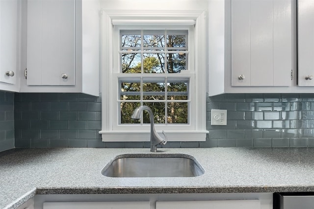 kitchen featuring white cabinets, light stone countertops, sink, and tasteful backsplash