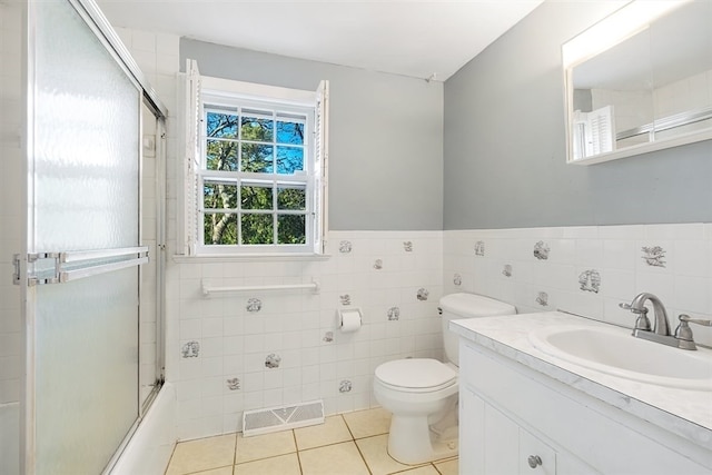 full bathroom featuring tile patterned flooring, combined bath / shower with glass door, toilet, vanity, and tile walls