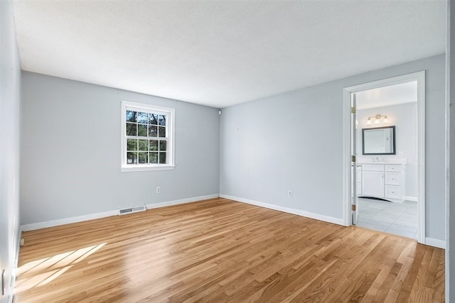 empty room featuring light wood-type flooring and a textured ceiling