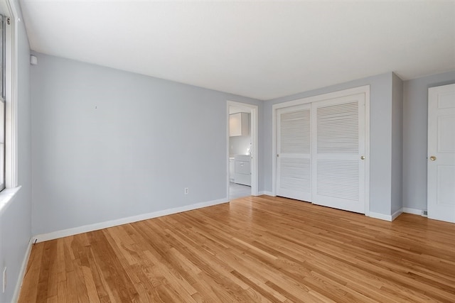 unfurnished bedroom with washer / dryer, a closet, and light wood-type flooring