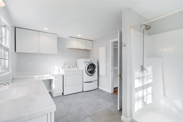 laundry area featuring washer and clothes dryer, cabinets, light tile patterned floors, and sink