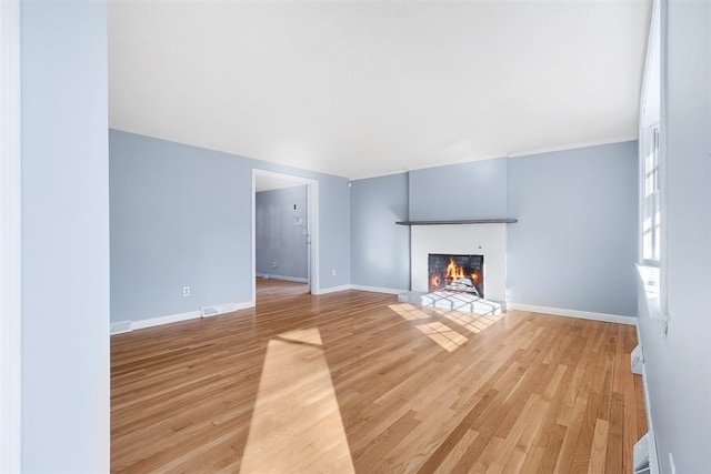 unfurnished living room featuring light wood-type flooring and a brick fireplace