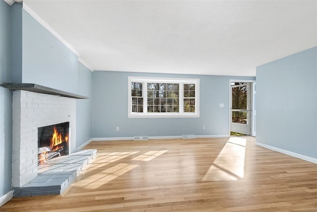 unfurnished living room with light wood-type flooring, a fireplace, and ornamental molding