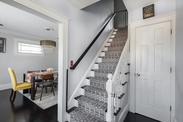 staircase with hardwood / wood-style floors, a chandelier, and ornamental molding