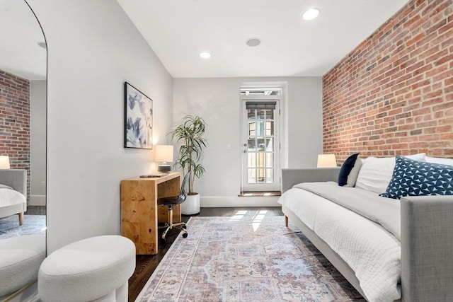 bedroom featuring recessed lighting, brick wall, baseboards, and wood finished floors