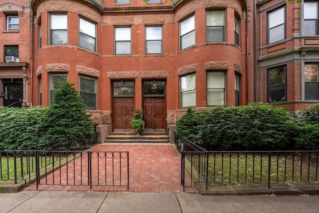 entrance to property featuring brick siding and fence