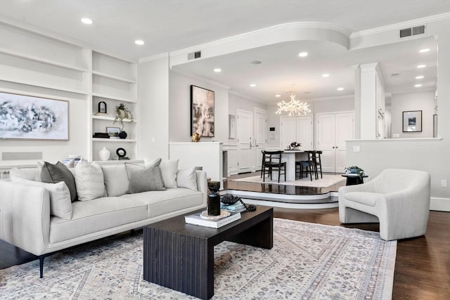 living area with visible vents, a notable chandelier, ornamental molding, wood finished floors, and recessed lighting