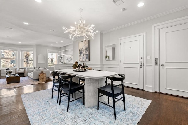 dining space featuring an inviting chandelier, crown molding, recessed lighting, and dark wood-type flooring