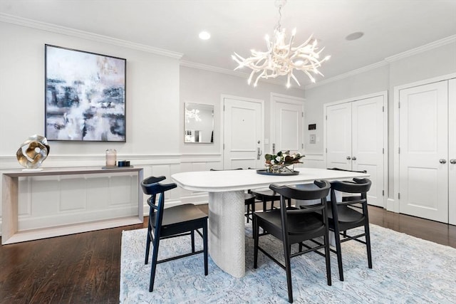 dining room with a decorative wall, crown molding, a wainscoted wall, wood finished floors, and a notable chandelier