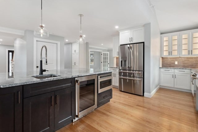 kitchen with stainless steel refrigerator with ice dispenser, backsplash, white cabinetry, a sink, and beverage cooler