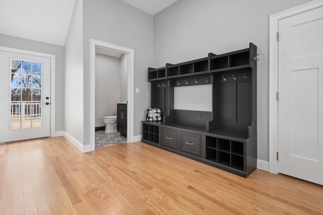 mudroom with light wood-style floors, baseboards, and vaulted ceiling