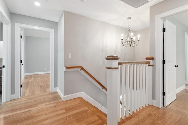 stairs with an inviting chandelier, baseboards, and wood finished floors