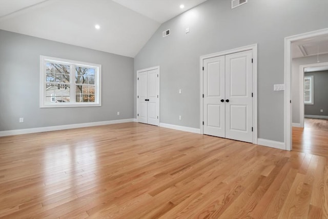 unfurnished bedroom with attic access, baseboards, visible vents, light wood-style flooring, and two closets