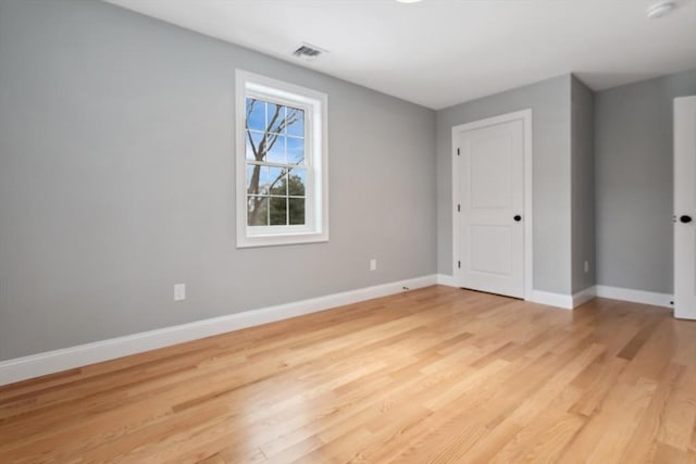 empty room featuring light wood-style floors, visible vents, and baseboards