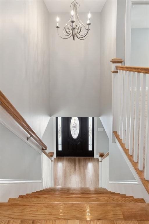 foyer entrance featuring wood finished floors, a notable chandelier, and stairs