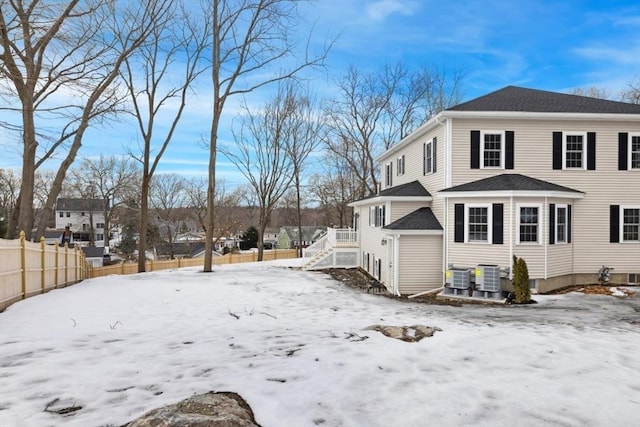 view of snow covered exterior with cooling unit and fence