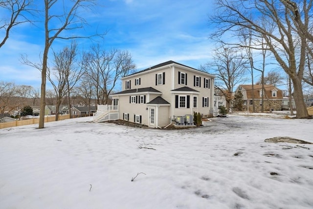 snow covered property with fence and stairs