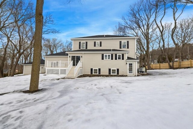 snow covered rear of property featuring fence and a deck