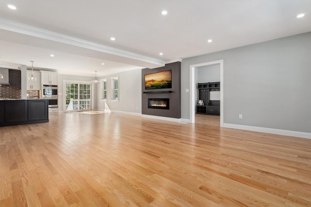 unfurnished living room featuring recessed lighting, light wood-type flooring, a glass covered fireplace, and baseboards