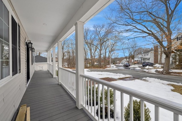 snow covered deck with covered porch and a residential view