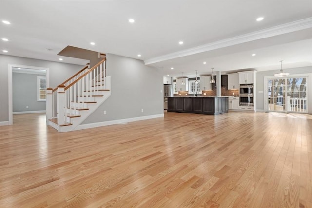 unfurnished living room with baseboards, light wood finished floors, stairway, and recessed lighting