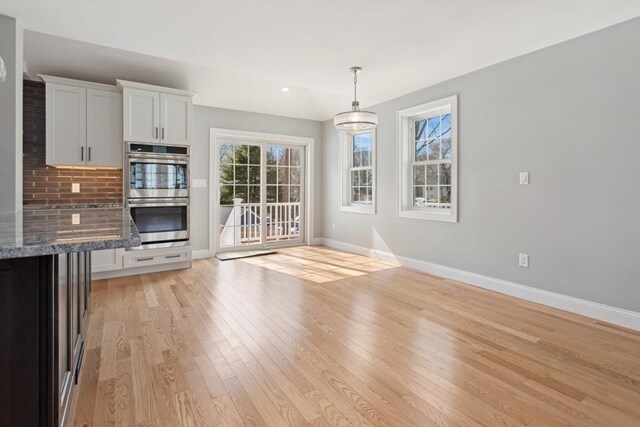 unfurnished living room with light wood-style flooring and baseboards