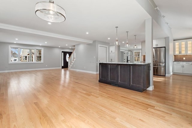 kitchen featuring baseboards, backsplash, high end fridge, light wood-style floors, and a sink