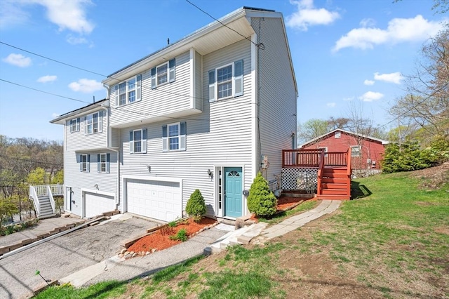 view of front facade with aphalt driveway, a garage, a deck, a front yard, and stairway