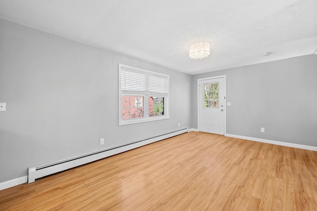 spare room featuring baseboards, a notable chandelier, wood finished floors, and a baseboard radiator
