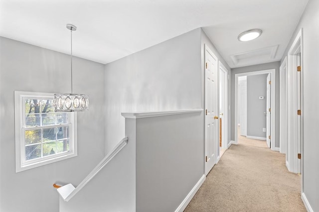 hall featuring carpet floors, baseboards, and an upstairs landing