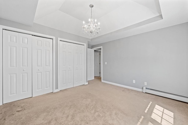 unfurnished bedroom featuring two closets, baseboards, a baseboard radiator, carpet, and a notable chandelier