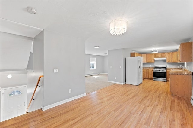 kitchen featuring stainless steel stove, baseboards, white refrigerator with ice dispenser, under cabinet range hood, and light wood-style flooring