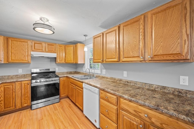kitchen featuring stainless steel gas range, white dishwasher, a sink, light wood-style flooring, and under cabinet range hood