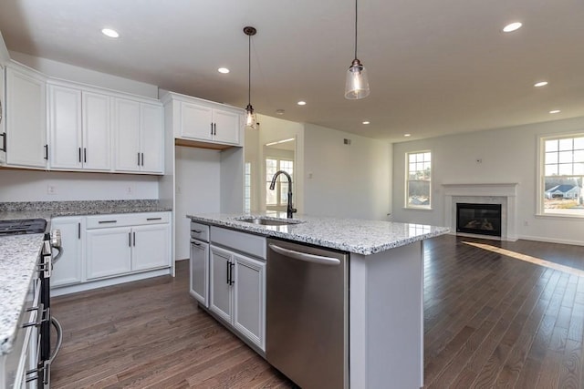 kitchen with sink, hanging light fixtures, an island with sink, white cabinetry, and stainless steel appliances