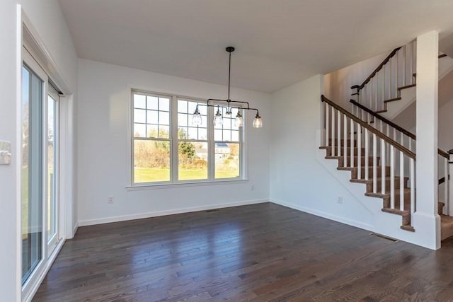 unfurnished dining area with a wealth of natural light, dark hardwood / wood-style floors, and a notable chandelier