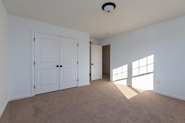 unfurnished bedroom featuring light colored carpet and a closet