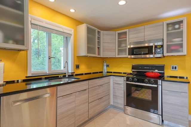 kitchen with appliances with stainless steel finishes, a sink, recessed lighting, dark stone counters, and modern cabinets
