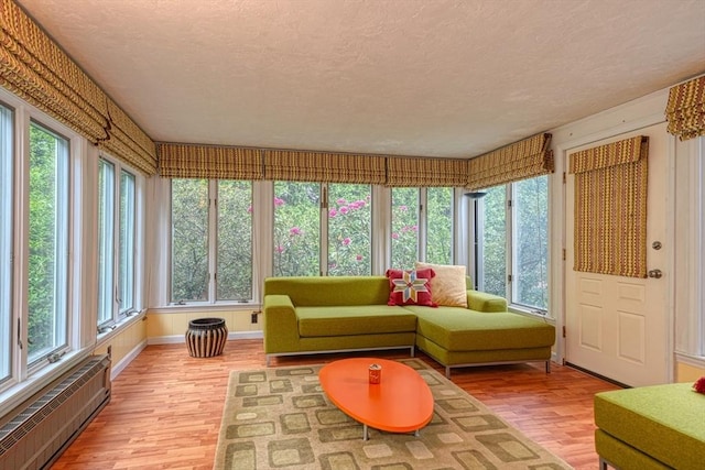 sunroom / solarium featuring wood finished floors, a textured ceiling, plenty of natural light, and radiator heating unit