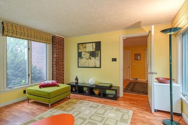 sitting room featuring light wood-style floors, a textured ceiling, and baseboards